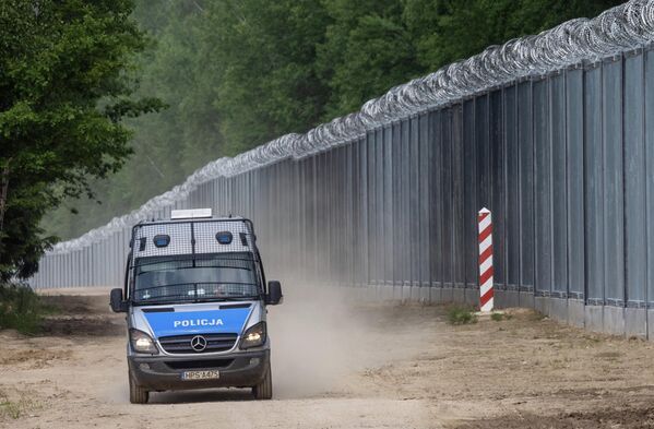 سيارة شرطة تقوم بدوريات على طول الجدار الحدودي عند الحدود البولندية البيلاروسية بالقرب من قرية تولتش، في مقاطعة سوكولكا، محافظة بودلاسكي، في شمال شرق بولندا في 8 يونيو 2022 - سبوتنيك عربي