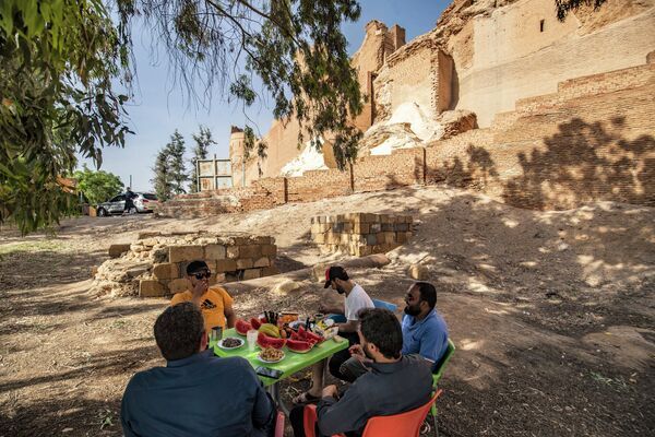 رجال يتناولون الطعام في الهواء الطلق بجوار قلعة جعبر بالقرب من خزان بحيرة الأسد بمحافظة الرقة في 3 يونيو 2022 - سبوتنيك عربي